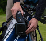 Person attaching a device to a golf bag on a golf course